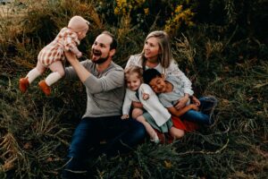 Dad lifting his baby girl in the air during a photo session while he laughs.