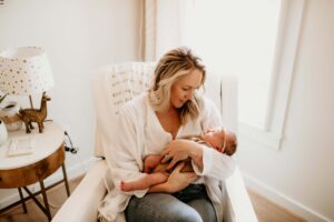 Mother holding her newborn baby girl in her nursery.