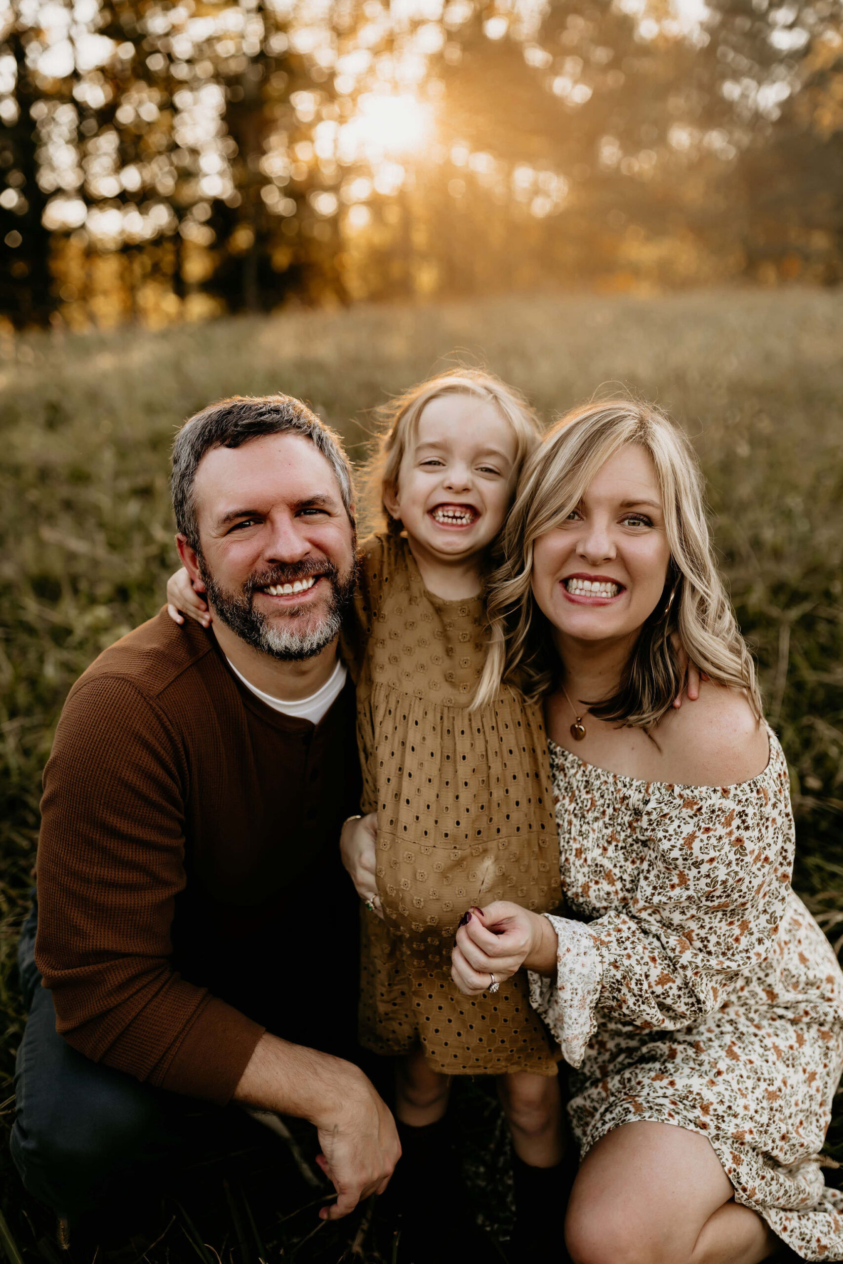 Mom, dad and daughter smiling during family photos