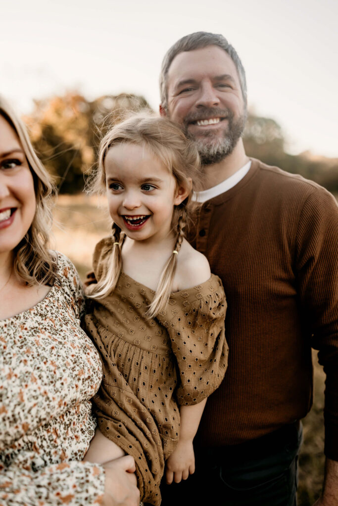 Mom, dad and daughter smiling during family photos